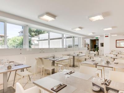 Ristorante moderno con arredi bianchi e tavoli apparecchiati.