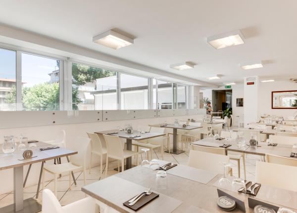 Restaurant moderne avec décor blanc et tables dressées.