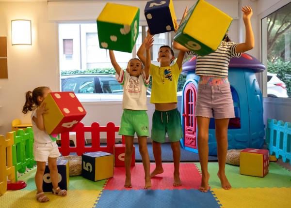 Kinder spielen mit bunten Würfeln in einem Spielzimmer.