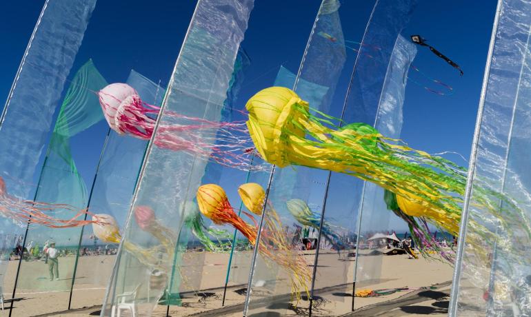 Aquiloni a forma di meduse colorate su una spiaggia soleggiata.