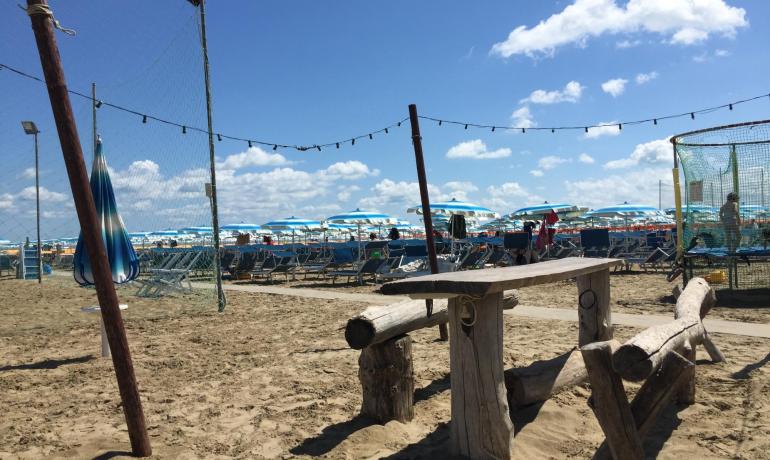 Beach with blue umbrellas and wooden table.