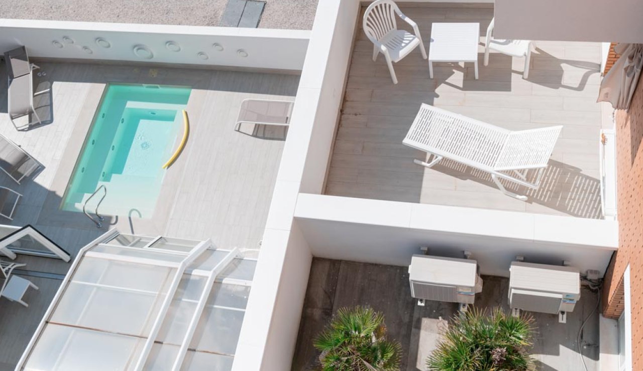 Vista dall'alto di una terrazza con piscina, lettini e mobili da giardino.