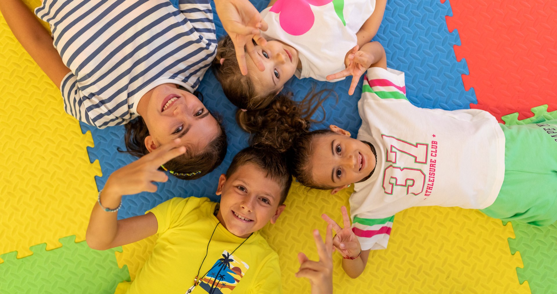 Famiglia felice in spiaggia, bambini sorridenti e genitori che si godono il tramonto.