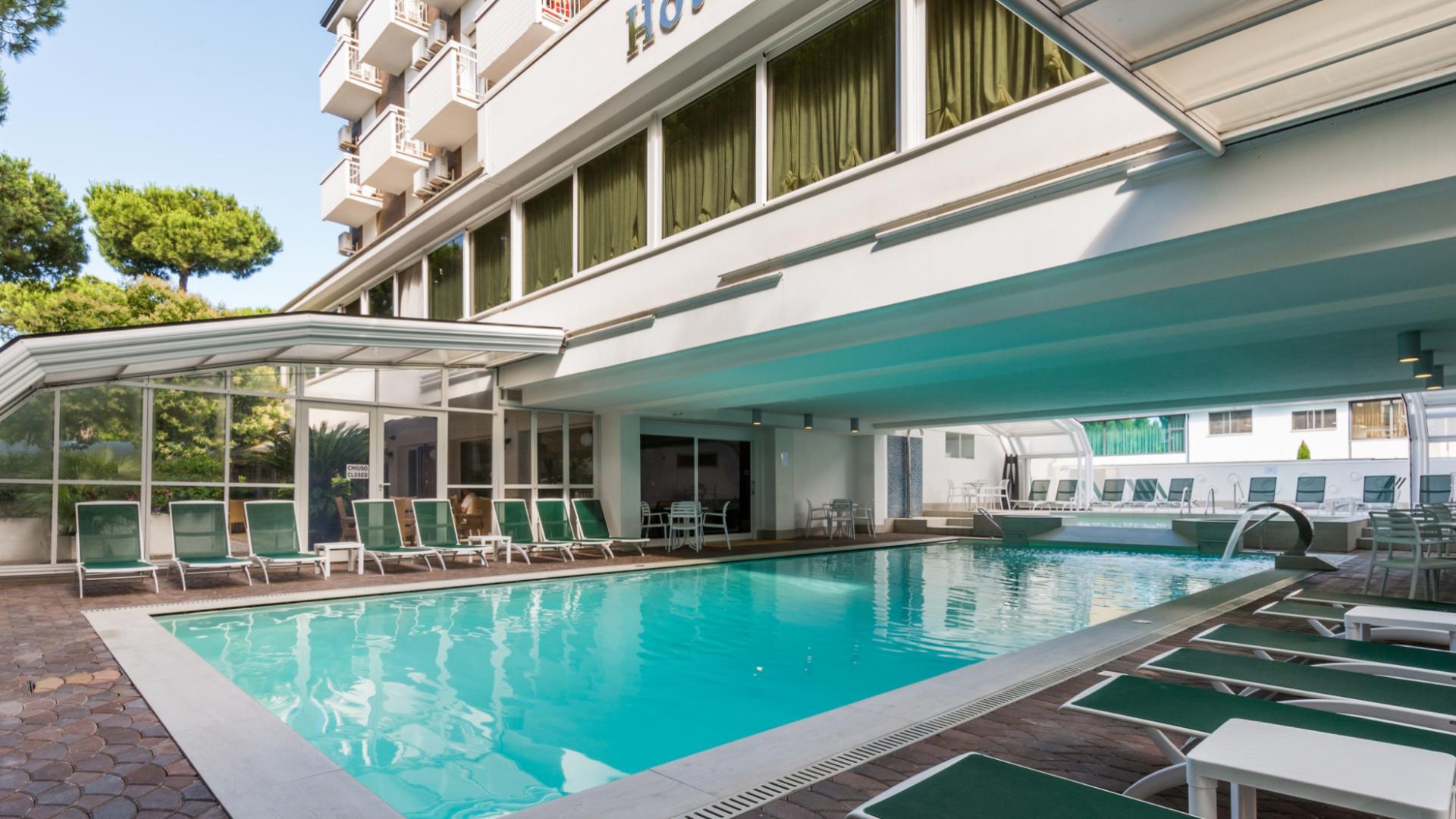 Piscina coperta di un hotel con lettini verdi e area relax.