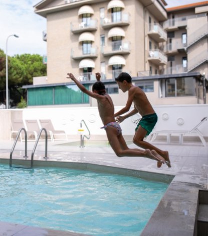 Due persone saltano insieme in una piscina all'aperto in un ambiente urbano.