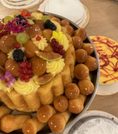 Dessert decorato con frutta e bignè su un tavolo con piatti.