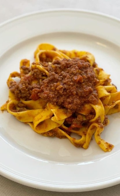 Tagliatelle al ragù di carne su piatto bianco, delizioso piatto italiano.