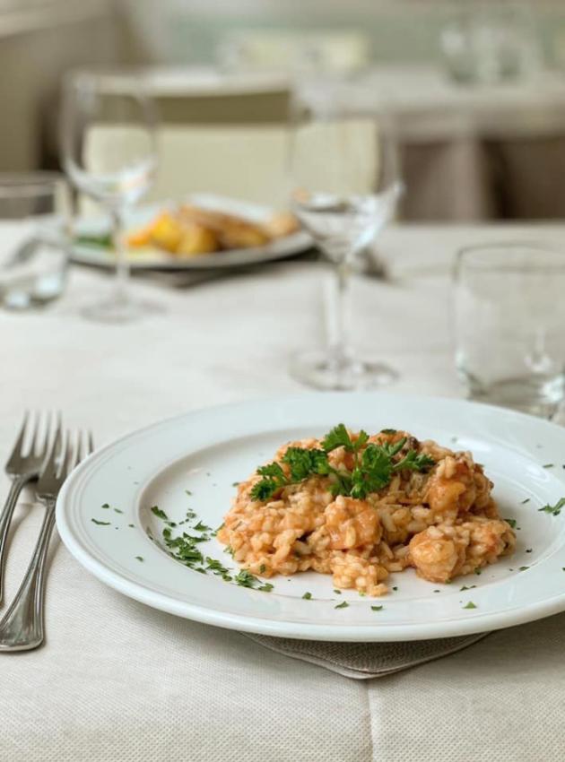 Risotto ai gamberi con prezzemolo, servito in un elegante ristorante.