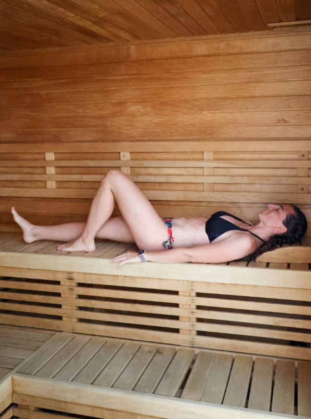 Donna in bikini che si rilassa in una sauna di legno.