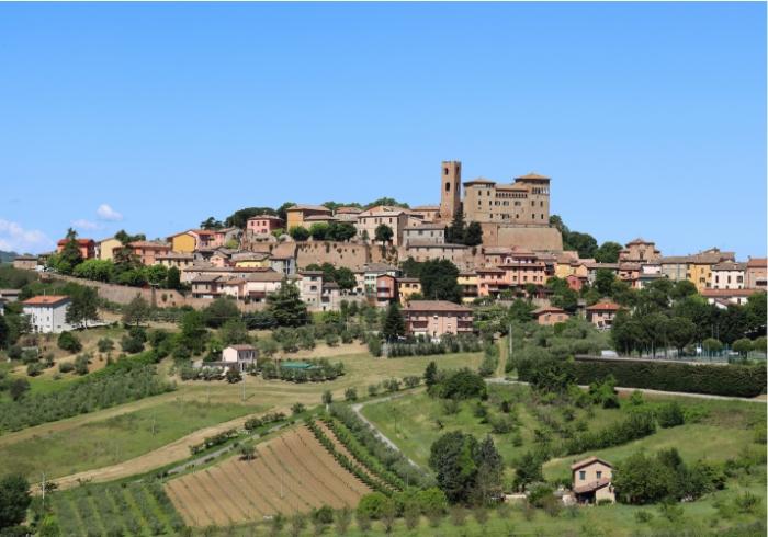 Un pittoresco borgo italiano con case colorate e una storica torre in cima alla collina.