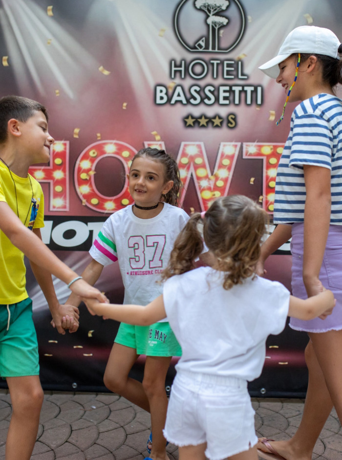 Bambini che giocano davanti all'insegna dell'Hotel Bassetti.