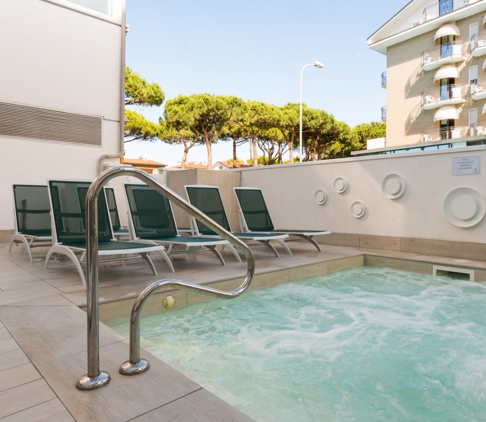 Persone in piscina coperta, relax e divertimento in un ambiente luminoso e moderno.