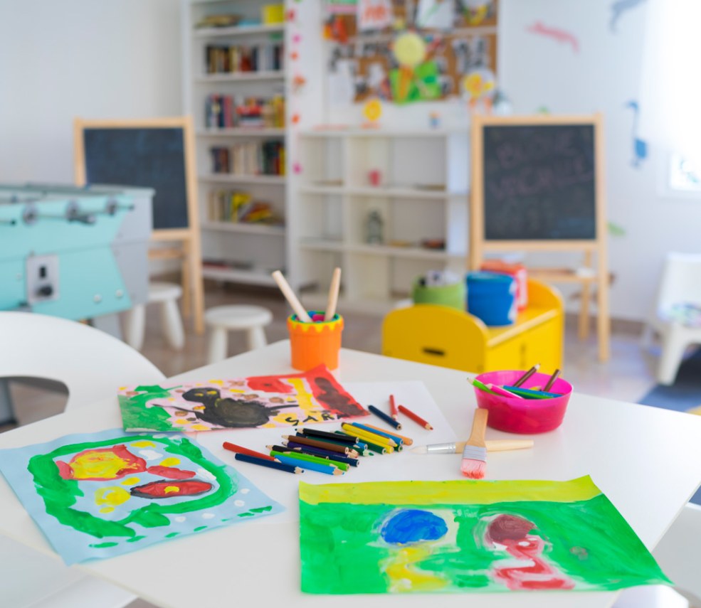 Bambina felice con volto e mani dipinti di colori vivaci all'aperto.