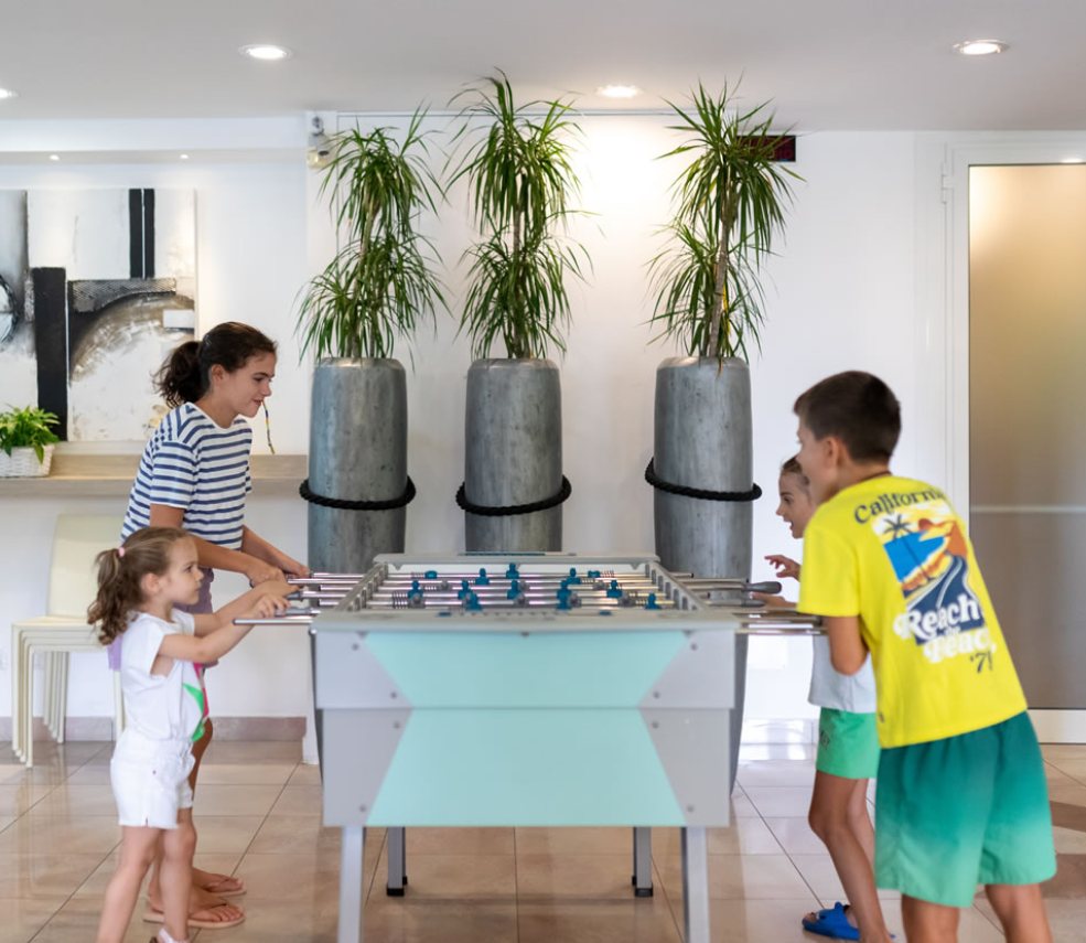 Famiglia gioca a calcio balilla in un ambiente moderno e luminoso.